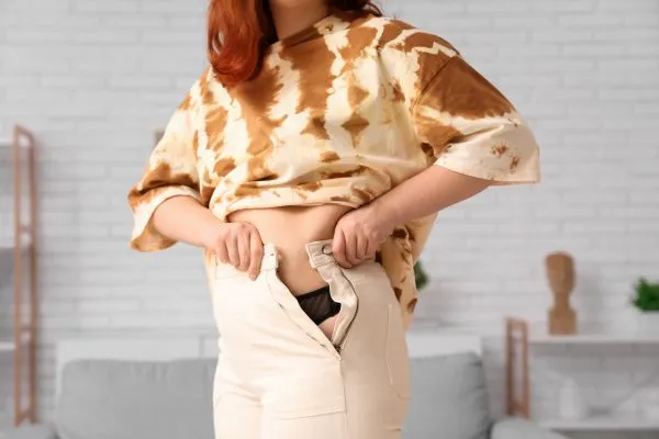 Image of woman trying to do her trousers up after pregnancy weight gain Margate
