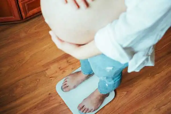 Image of woman weighing herself and experiencing weight gain through pregnancy Margate