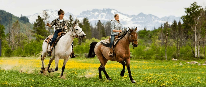 Confident plus-size woman riding Margate a horse through a field with a smile on her face.